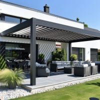 A modern and stylish black aluminum patio cover with white slats, standing on the lawn of an elegant house in Germany. The roof covers part of the garden area where there is furniture for relaxing or having family gatherings. In summer, bright sunlight illuminates the scene, creating a relaxed atmosphere. This image highlights how these patios can be used to create comfortable outdoor spaces in the style of these patios. --ar 128:85 --style raw --stylize 250 Job ID: 35d1f3c1-916d-4036-8c87-ae180947dce0